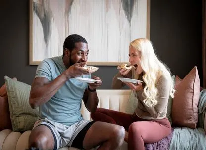 Couple eating pizza on a sofa in new build home at Knights Park