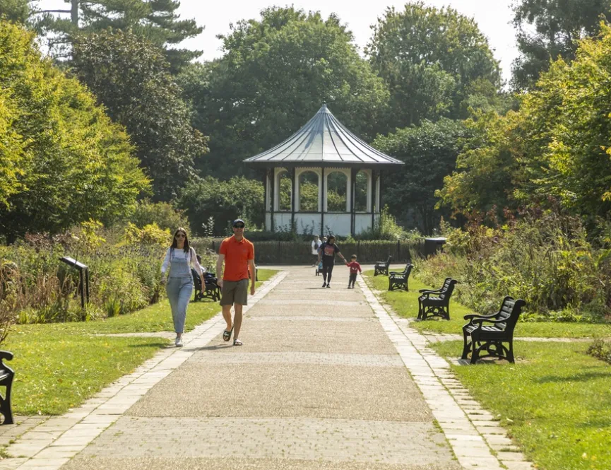 Young couple walking through a park with a pergola in the background
