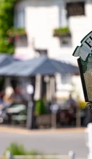 Historical Finchingfield sign with historical pub and pond in background