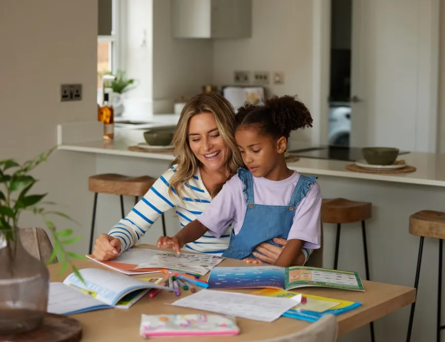 Mother and young child sat at a dining table doing homework