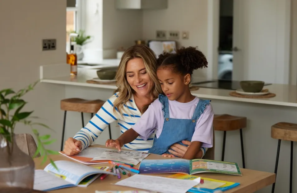 Mother and young child sat at a dining table doing homework