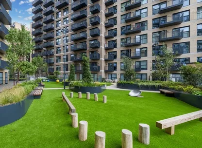 Green space with seating outside of a tall, modern apartment building in Brentford