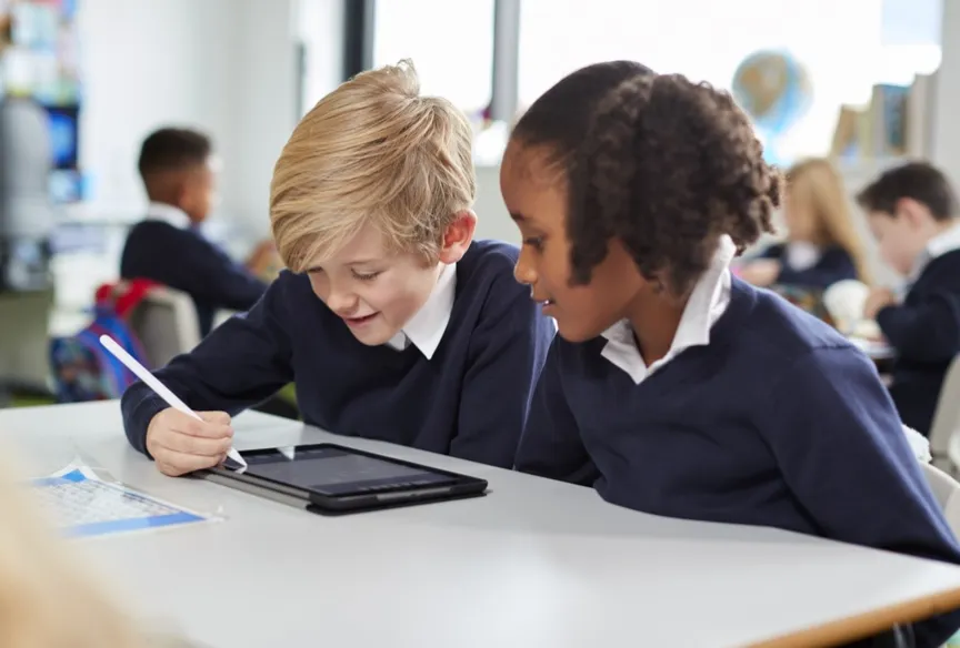 Two young pupils working on an ipad in a school
