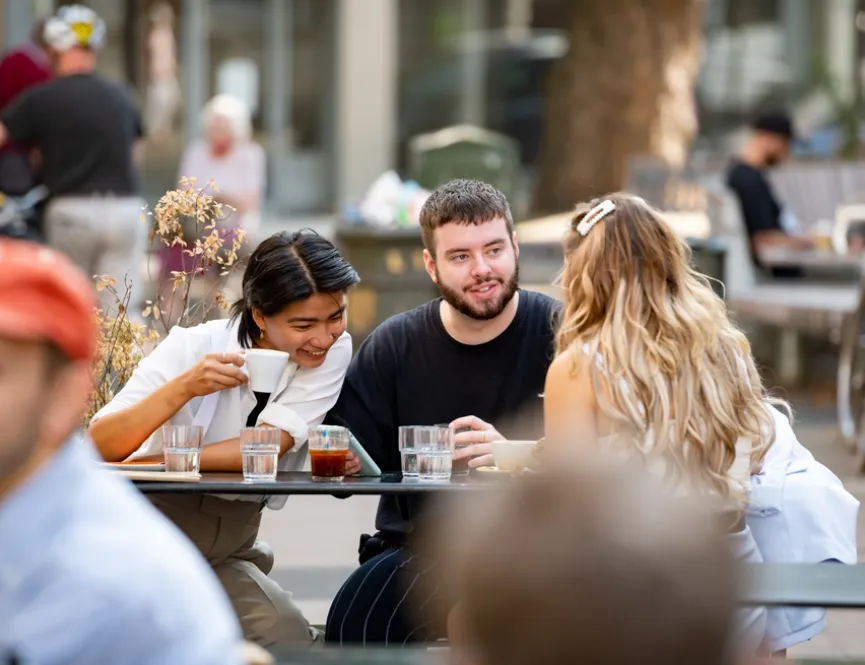 Group of young friends having drinks outside of a cafe